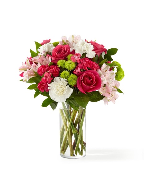 Bright pink roses, pink alstroemeria, white carnations and green mums in a clear glass vase