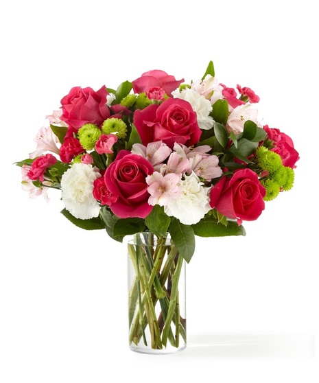 Bright pink roses, pink alstroemeria, white carnations and green mums in a clear glass vase